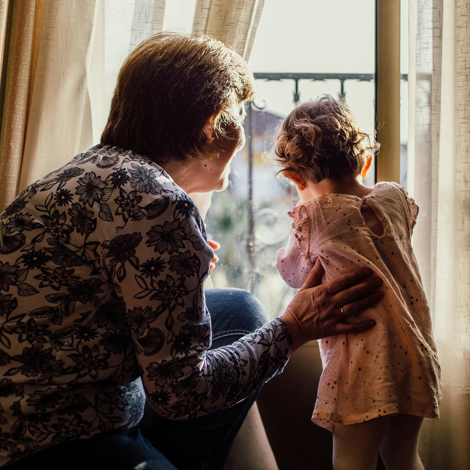 Grandmother looking out the window with granddaughter